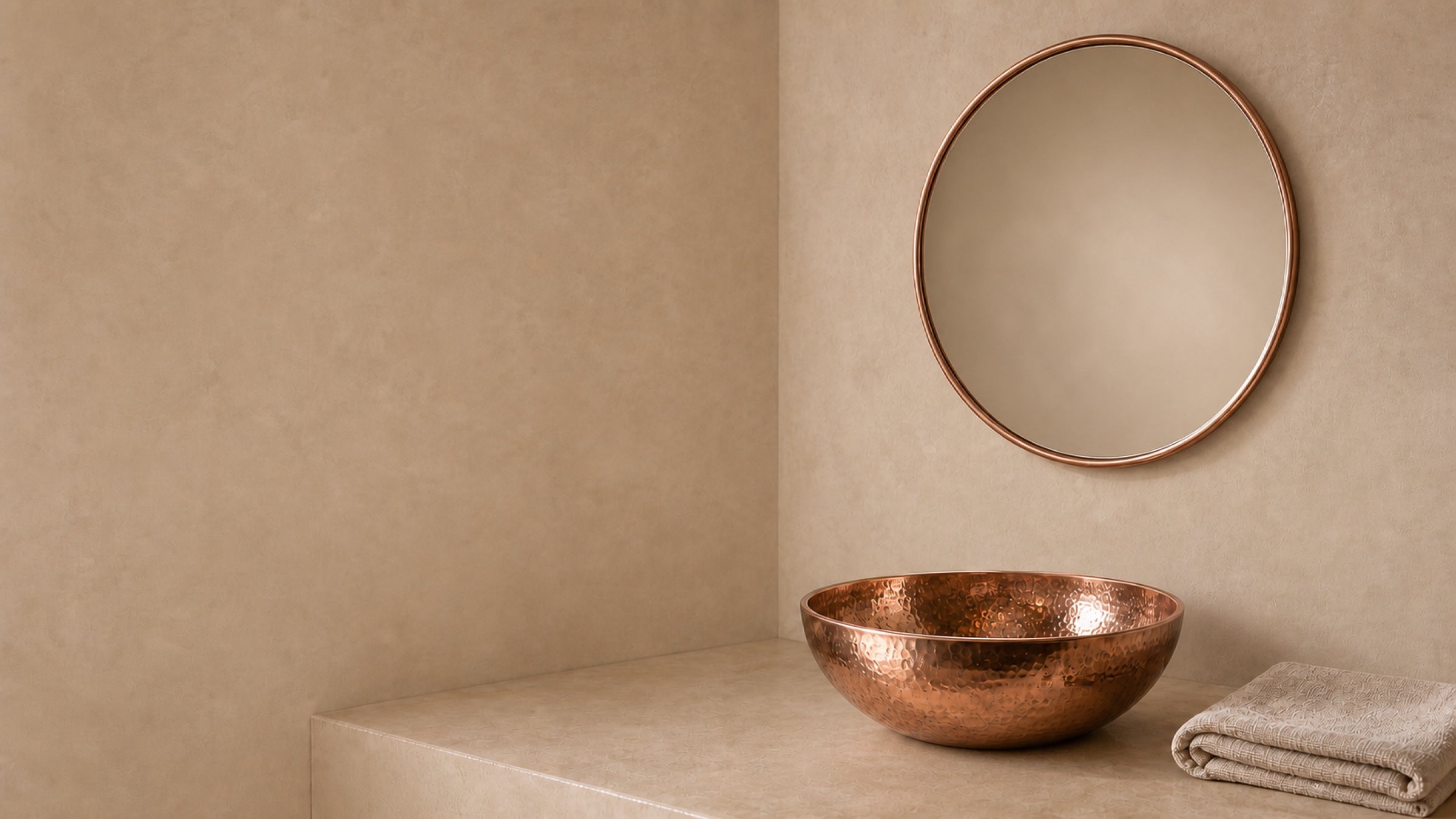 Hammered bronze basin and bronze-framed mirror in a warm mineral bathroom