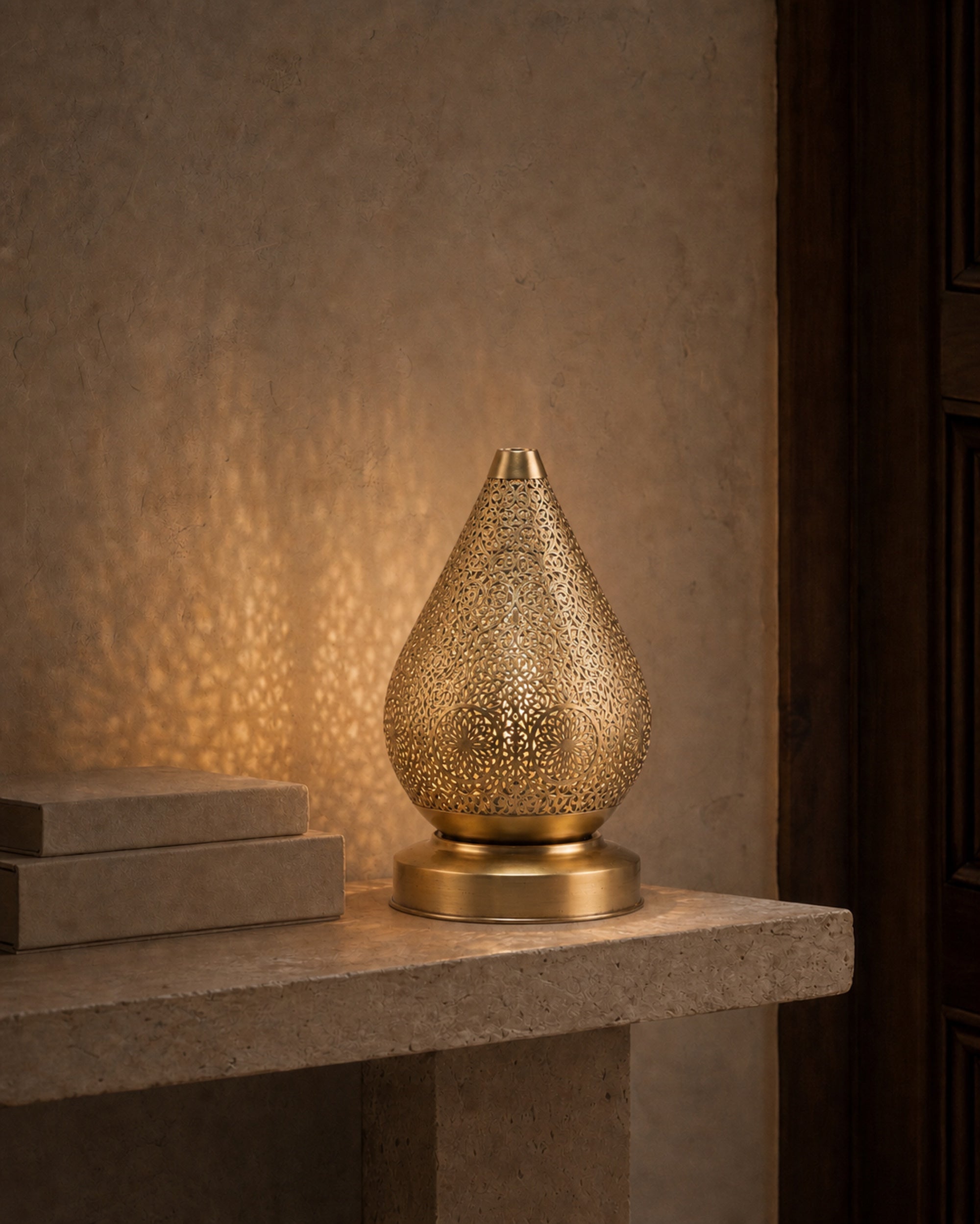 Perforated brass lamp casting a warm pattern of light on a mineral wall